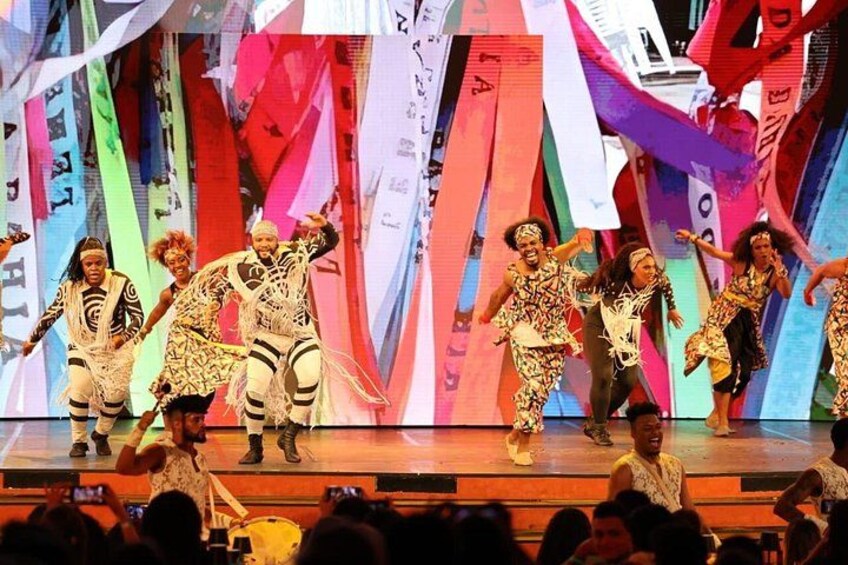 A group of dancers performing on a stage with colorful banners in the background. 5