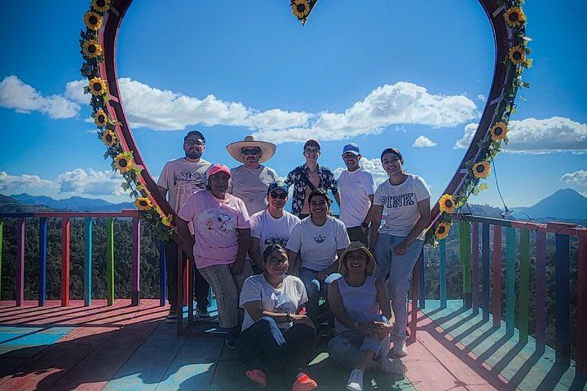 Un grupo de personas posando en una terraza colorida con una vista panorámica de montañas al fondo. 3