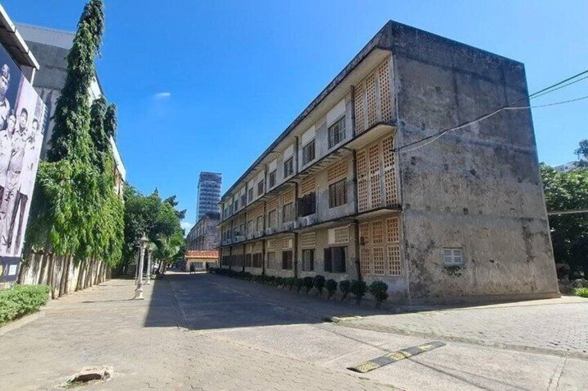 Una calle con edificios en fila, uno de ellos con un mural, y un cielo azul despejado. 2