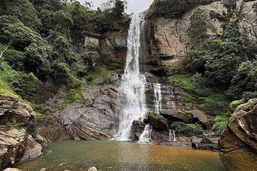 A waterfall cascading down a rocky cliff into a pool surrounded by lush greenery. 3