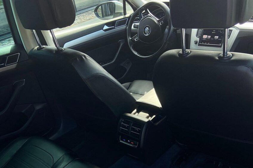 A car's interior with leather seats, a steering wheel, and a central console with controls. 2