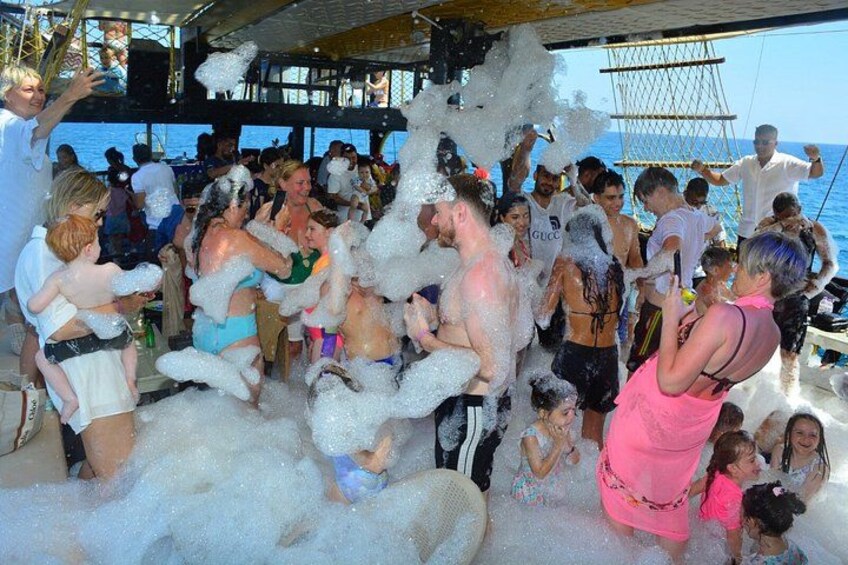A group of people on a boat surrounded by foam. 1