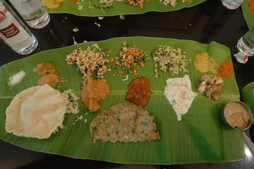 Una comida tradicional del sur de la India servida sobre una hoja de plátano, con diversos platos como arroz, curry y pan plano. 4
