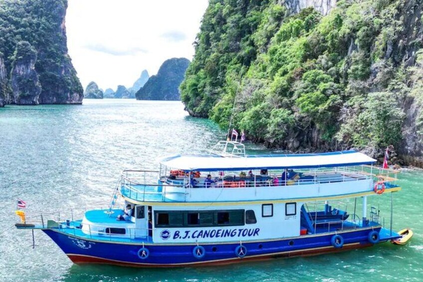 A boat named B.J. CANOEING TOUR on a calm river surrounded by lush green cliffs. 3