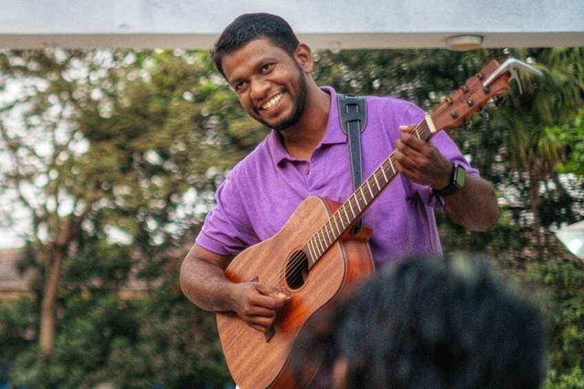 A person playing an acoustic guitar outdoors. 2