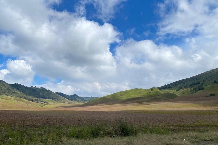 A landscape with rolling hills, a field, and a clear sky with clouds. 4