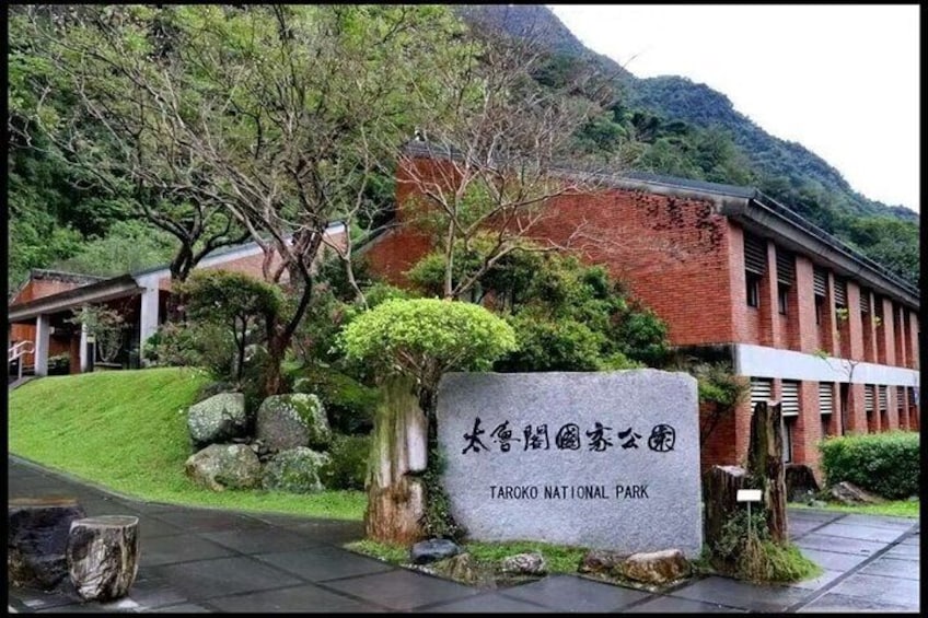 Taroko National Park entrance sign, lush greenery, and a traditional building. 4