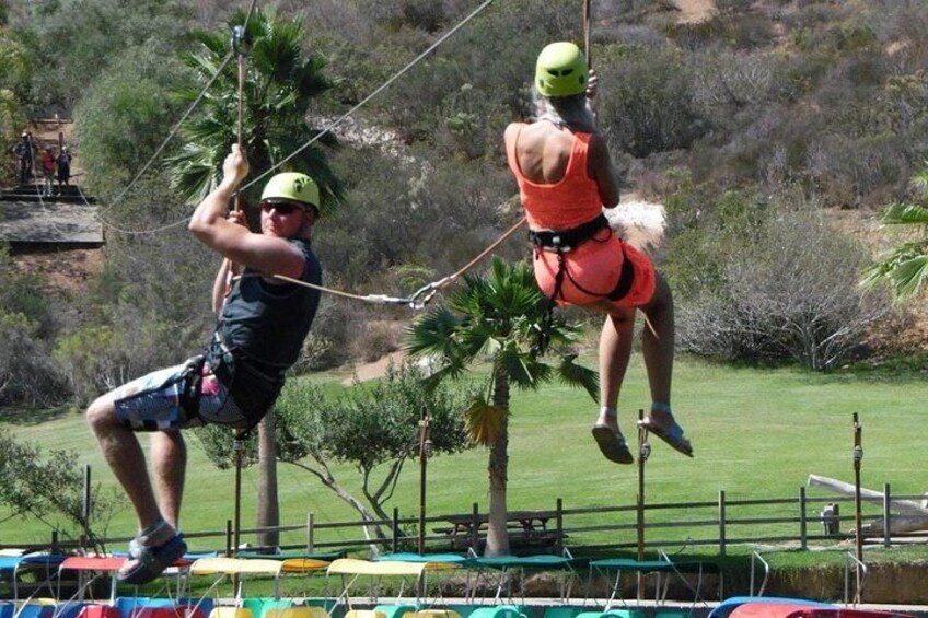 A person zip-lining with another person assisting. 4