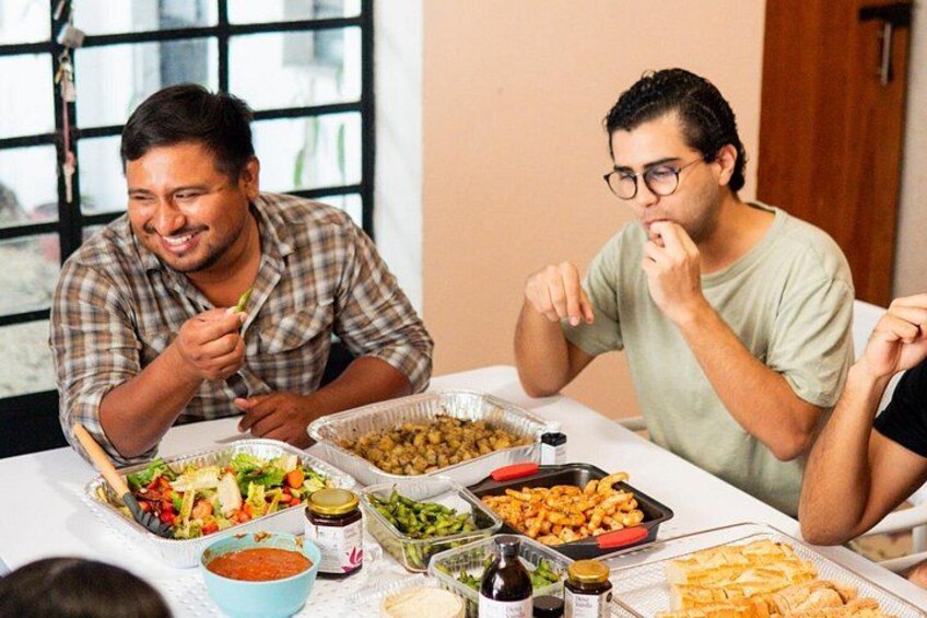 Dos hombres sentados en una mesa con varios platos y salsas. 4