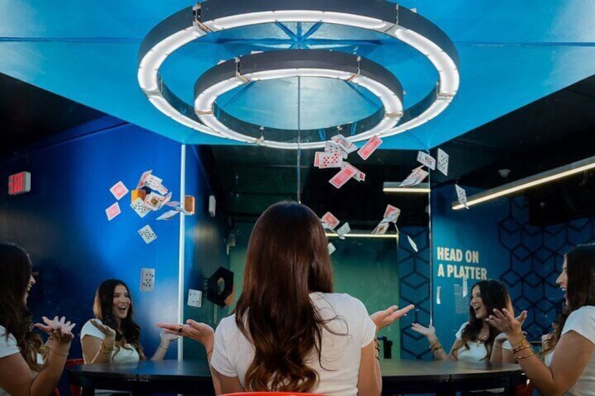 A room with a blue wall, a circular light fixture, and playing cards scattered on the wall. 2