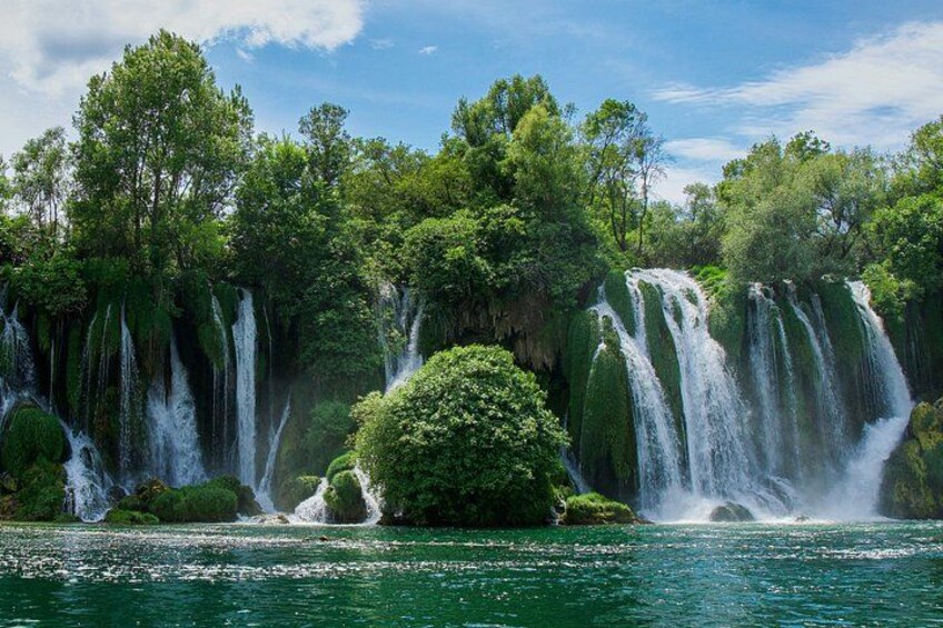 Una cascada se precipita sobre un bosque verde y exuberante hacia una masa de agua tranquila. 2