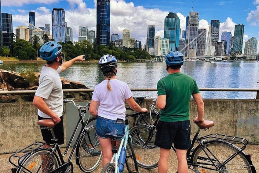 Three people on a bridge overlooking a city skyline with a river in the foreground. 5