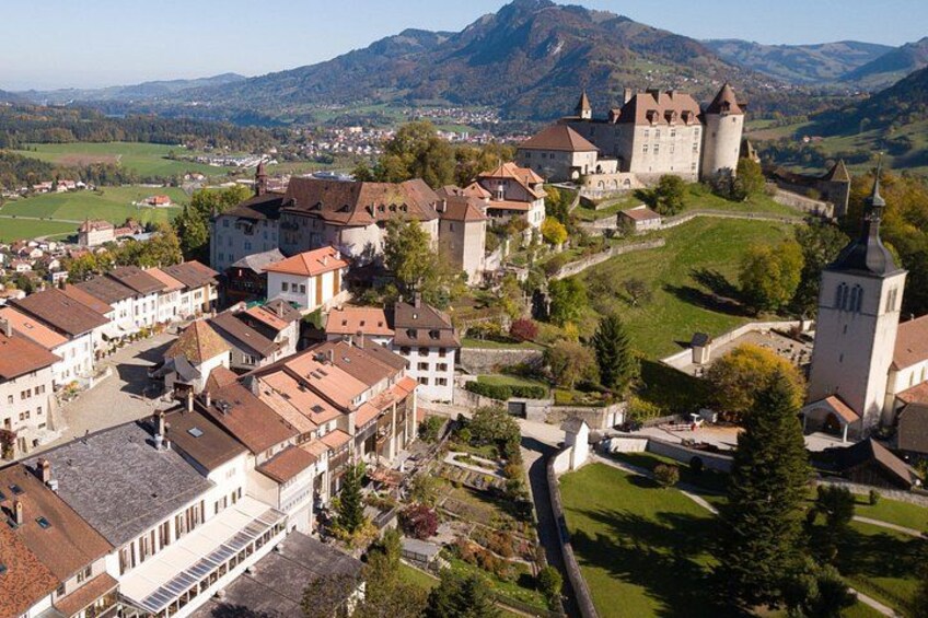 A historic town with a castle, church, and surrounding greenery. 1