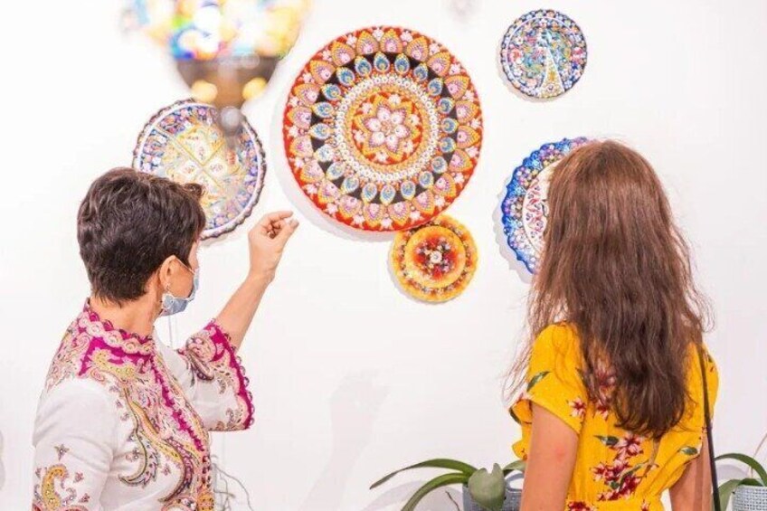 A person pointing at a wall decorated with colorful circular patterns. 3