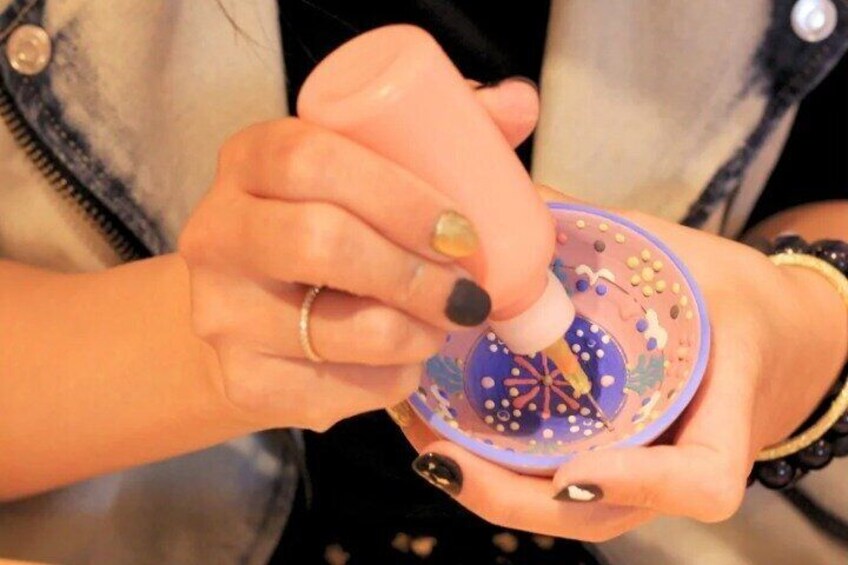 A person using a tool on a colorful, patterned object. 4