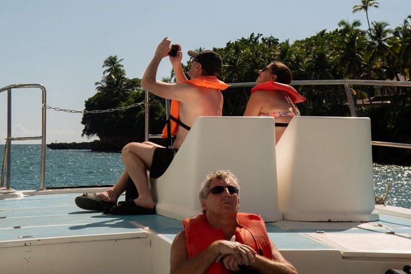 A boat with people wearing life jackets, a ladder, and a calm body of water with palm trees in the background. 4