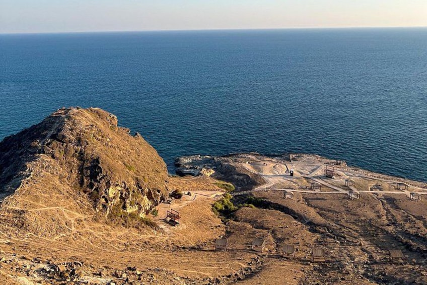 A coastal archaeological site with ruins and a large hill. 5