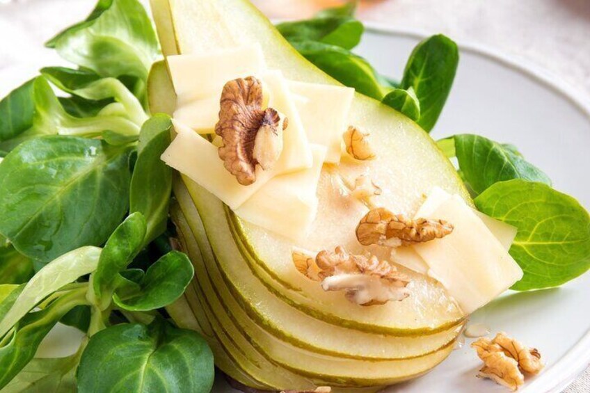 A plate with sliced apples, walnuts, and green leaves. 4
