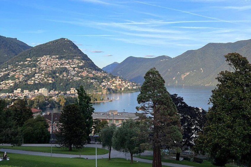 Un paisaje montañoso con un lago, árboles y un pueblo. 5