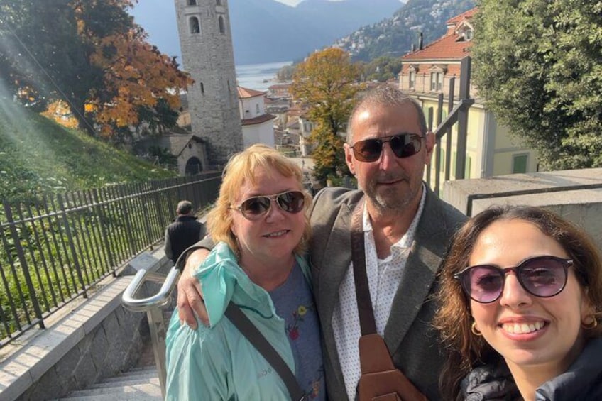 A group of people on a stone staircase with a view of a tower and buildings in the background. 2