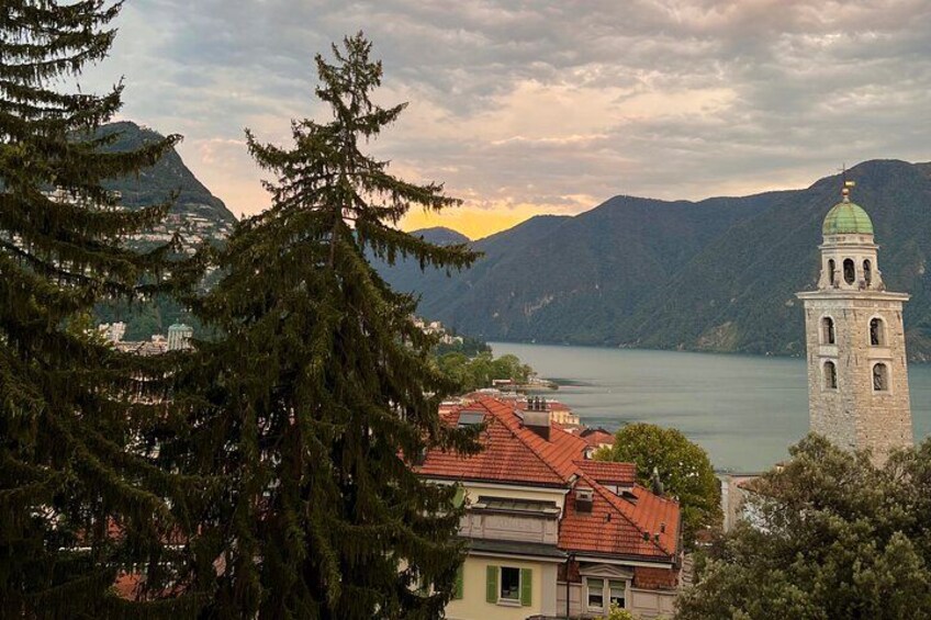 Un paisaje montañoso con un lago, una torre de iglesia y edificios residenciales. 2