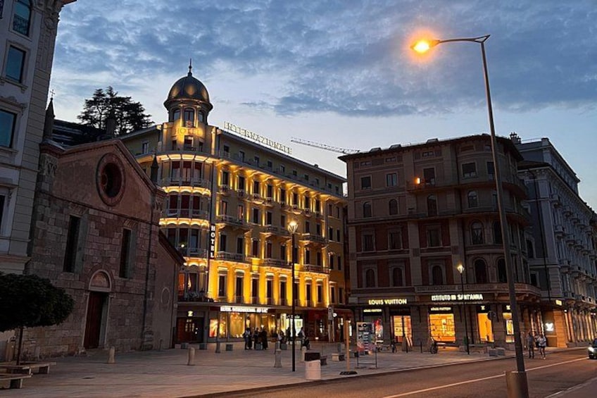 A historic building with a dome and illuminated facade, adjacent to a Louis Vuitton store. 3