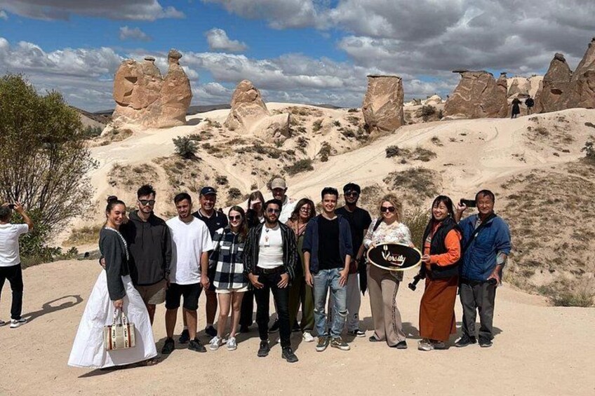 A group of people standing in a desert landscape with large rock formations in the background. 2