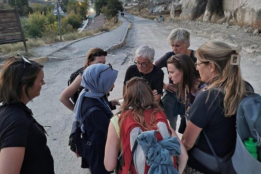 A group of hikers on a dirt path with rocky terrain and sparse vegetation. 3
