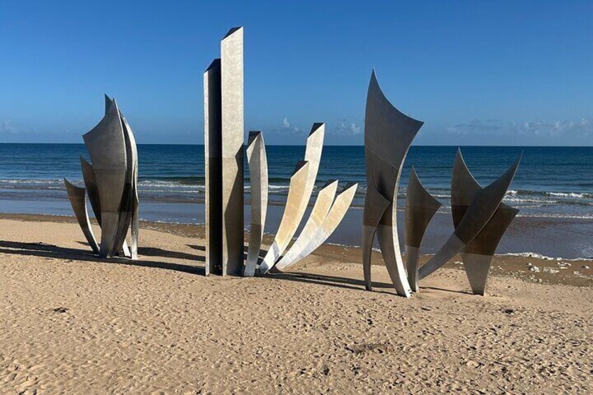 Des sculptures métalliques abstraites sur une plage, avec l’océan en arrière-plan. 4