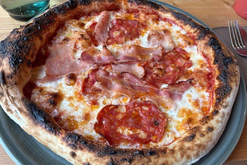 A pizza with ham and tomato sauce on a plate. 3