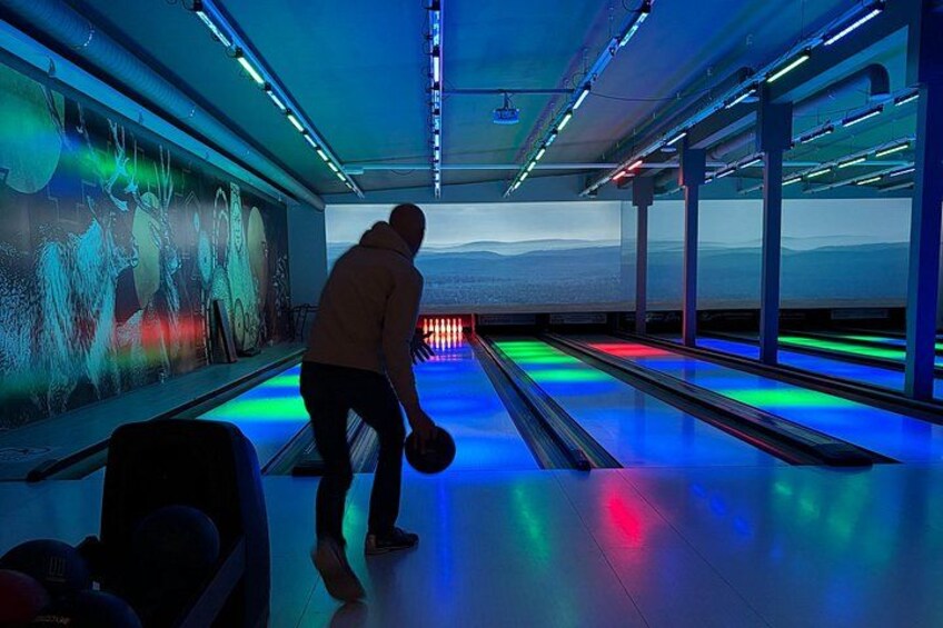 A bowling alley with illuminated lanes and a person bowling. 4