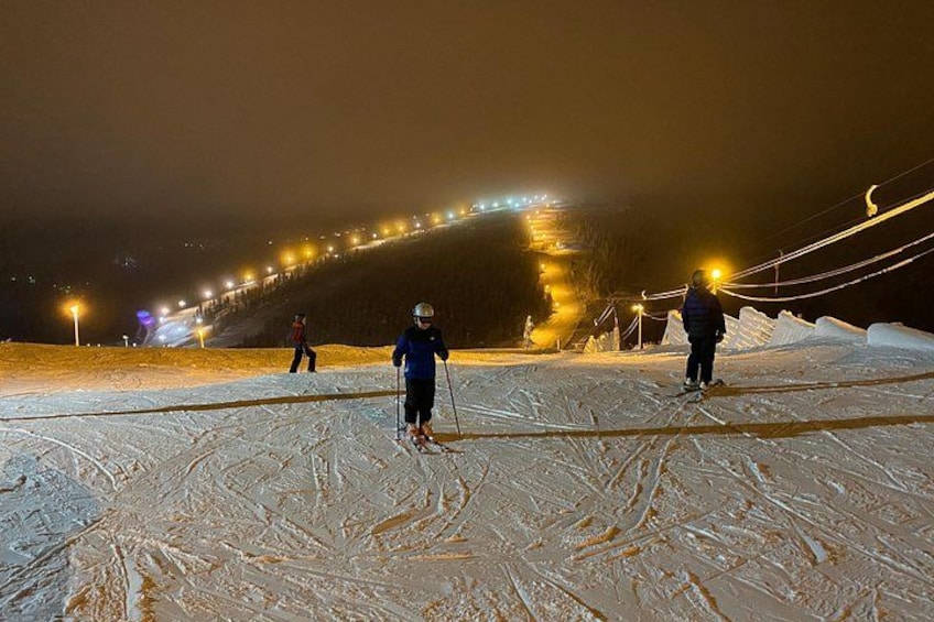 A snowy ski slope at night with artificial lighting. 5
