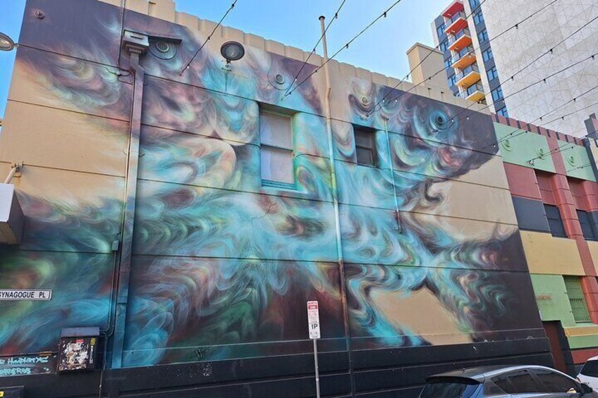 Un murale colorato su un edificio, caratterizzato da motivi vorticosi e un disegno di un pesce. 2