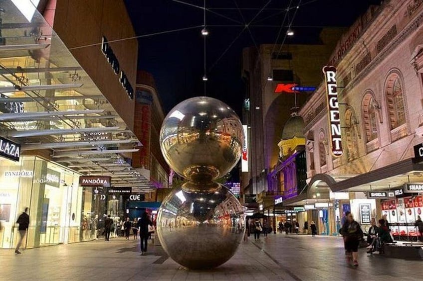 A shopping mall with a large spherical sculpture in the center, surrounded by various stores and architectural details. 1