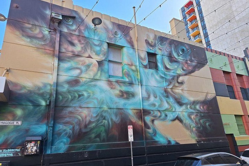 A colorful mural on a building with swirling patterns and a fish design. 2