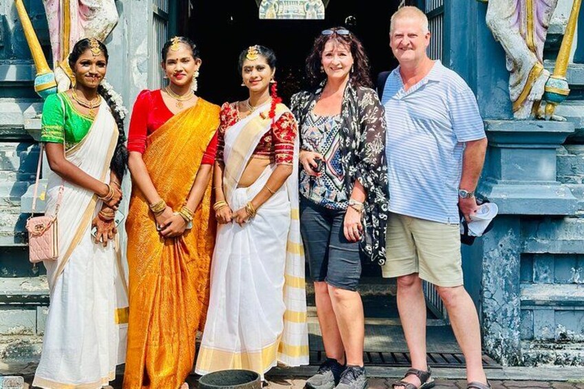 A group of people standing in front of a temple with stone carvings and a statue. 3