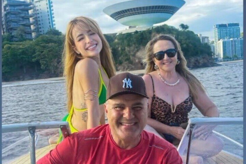 Un bote con tres personas, un cuerpo de agua y un edificio grande al fondo. 1