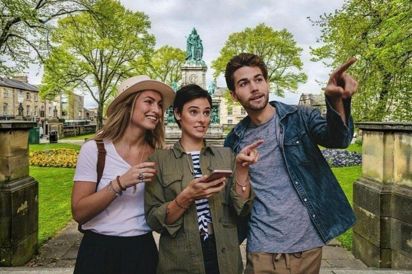 Three people standing in a park with a statue in the background. 1