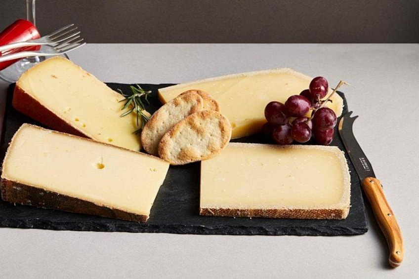 A cheese board with various cheeses, crackers, and grapes. 2