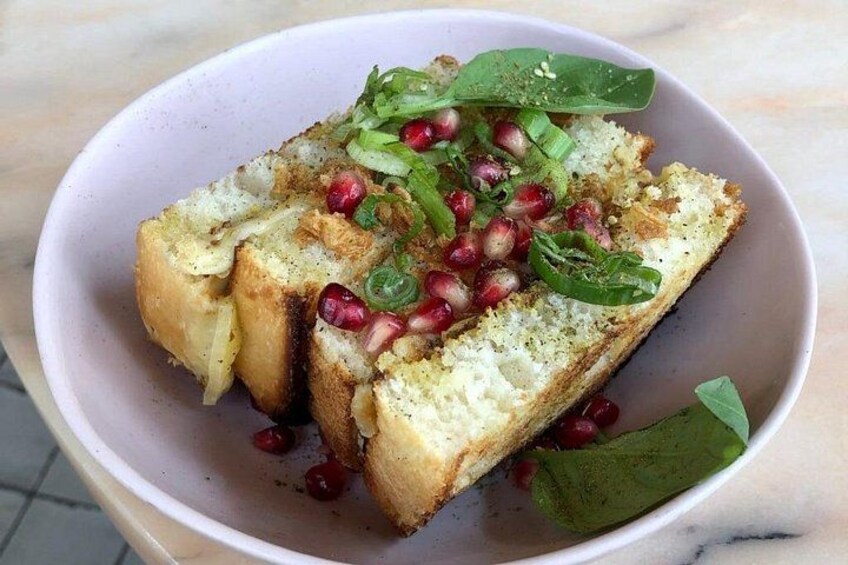 A bowl of toasted bread with pomegranate seeds and green onions. 3