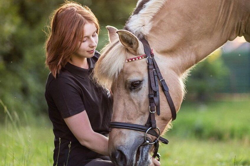 A person sitting next to a horse in a grassy field. 1