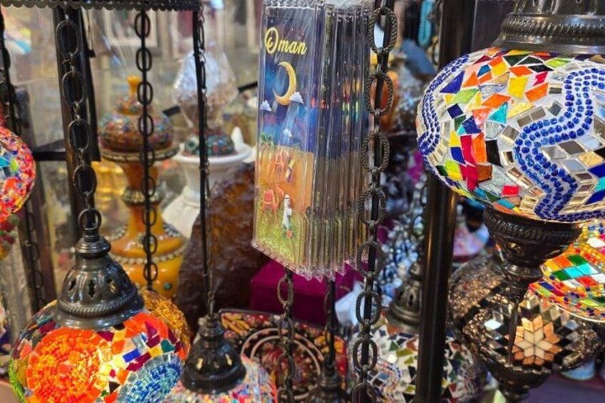 Una variedad de cristalería colorida, incluyendo jarras ornamentadas y pantallas, exhibida en una tienda. 3
