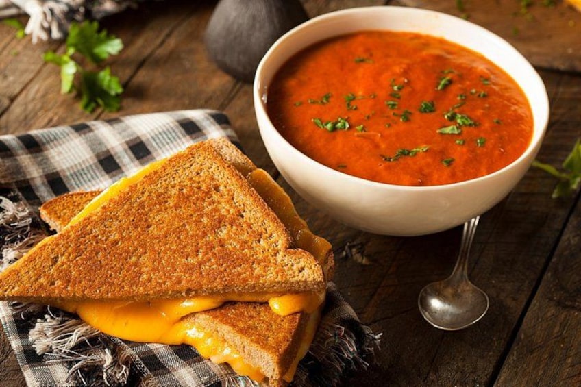 A grilled cheese sandwich with melted cheese and a bowl of tomato soup. 4