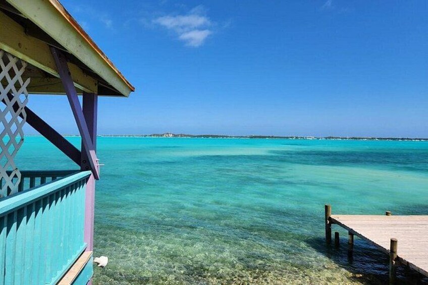 A turquoise beach with clear water, a wooden pier, and a blue structure. 2