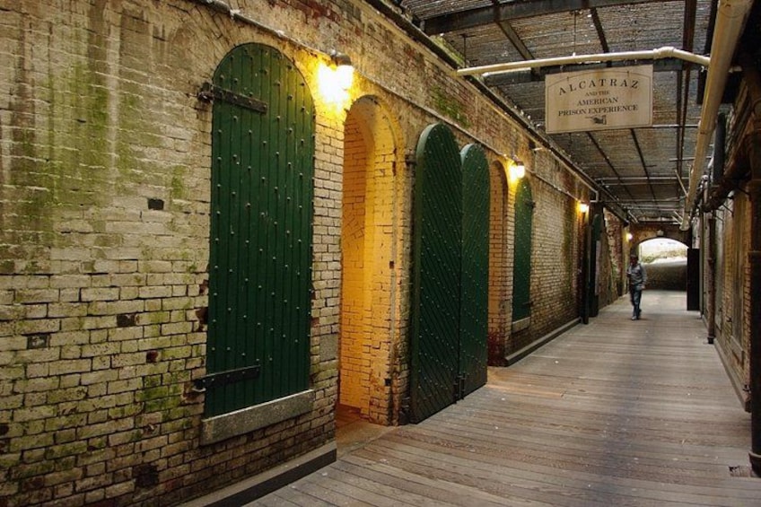 Ein Backsteingebäude mit grünen Türen und einem Schild, auf dem 'ALCATRAZ WESTERN AMERICAN PRISON EXPERIENCE' steht. 4