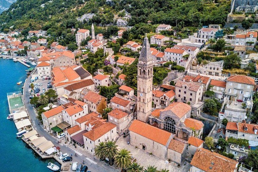 A coastal town with a prominent church, red-roofed buildings, and a clear blue sea. 5