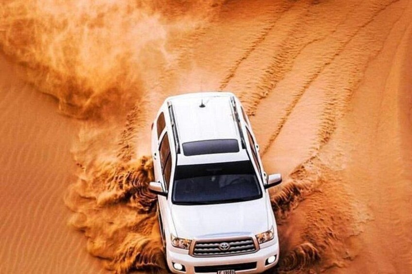 A white SUV driving through a sandy desert landscape. 2