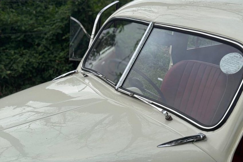 A vintage car with a sunroof, a steering wheel, and a door handle. 3