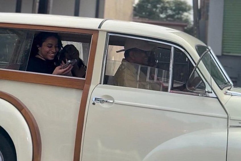 A vintage car with a wooden interior and a person holding a phone. 1