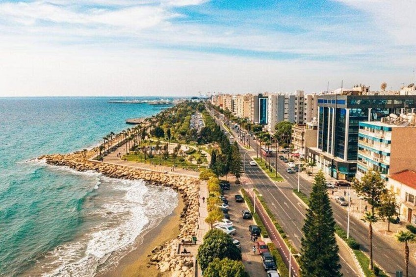 A coastal cityscape with a rocky shoreline, a promenade, and modern buildings. 2